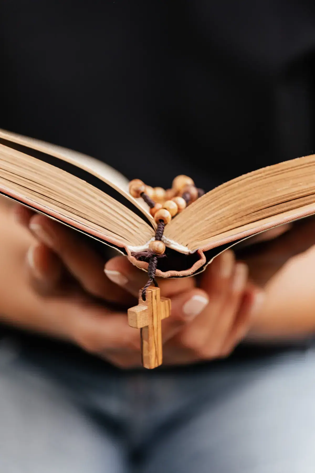 Two hands resting together over an open Bible during prayer for healing