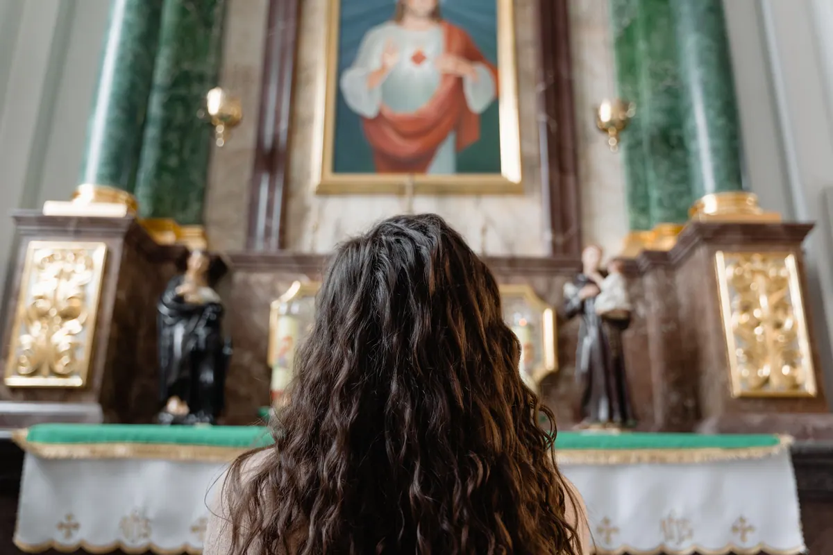 Woman kneeling in prayer inside a church seeking comfort