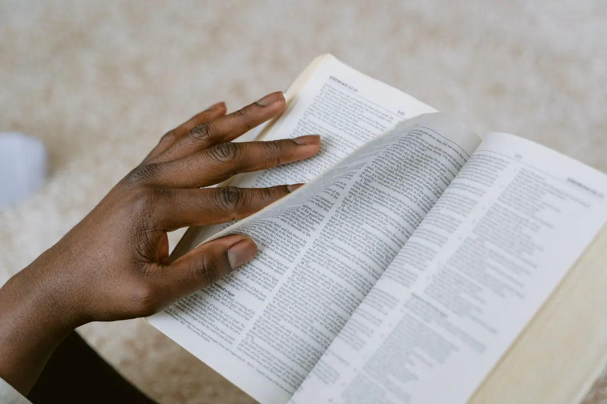 Person reading Scripture beside a peaceful stream