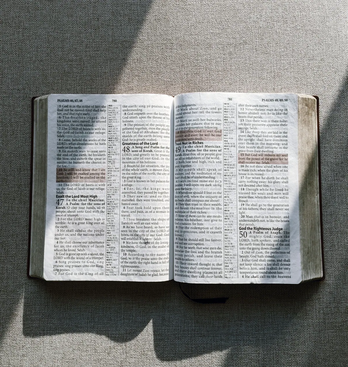 Open Bible on gray fabric with sunlight across the pages