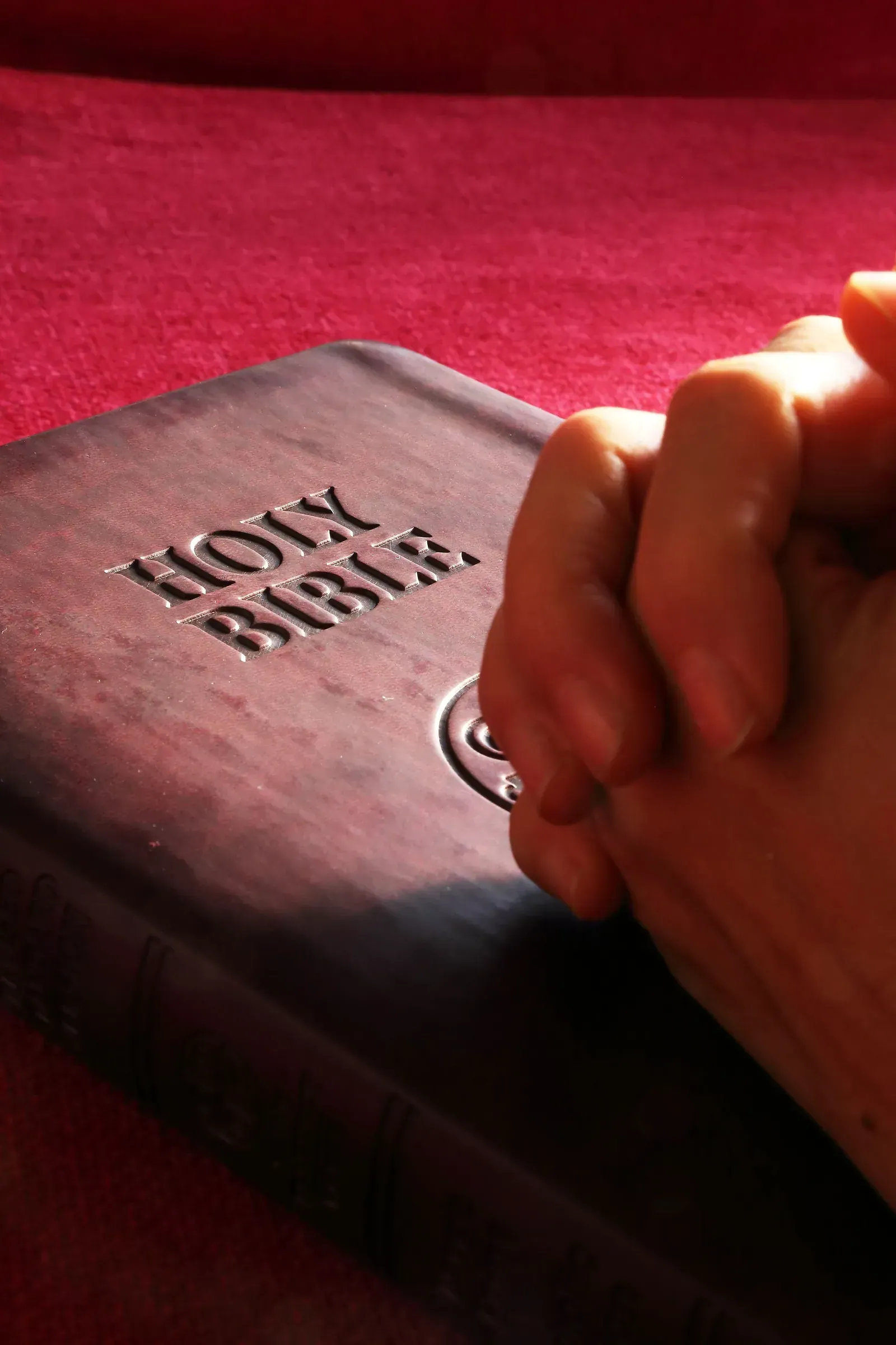 Hands clasped in prayer over an open Bible, representing James 5:14–15 and prayer for the sick