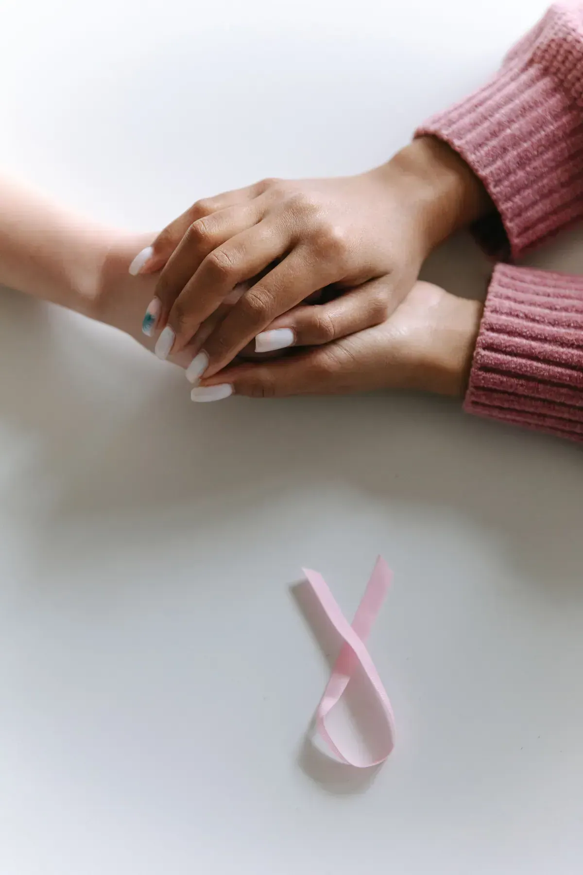 Hands holding a cancer awareness ribbon symbolizing support and encouragement