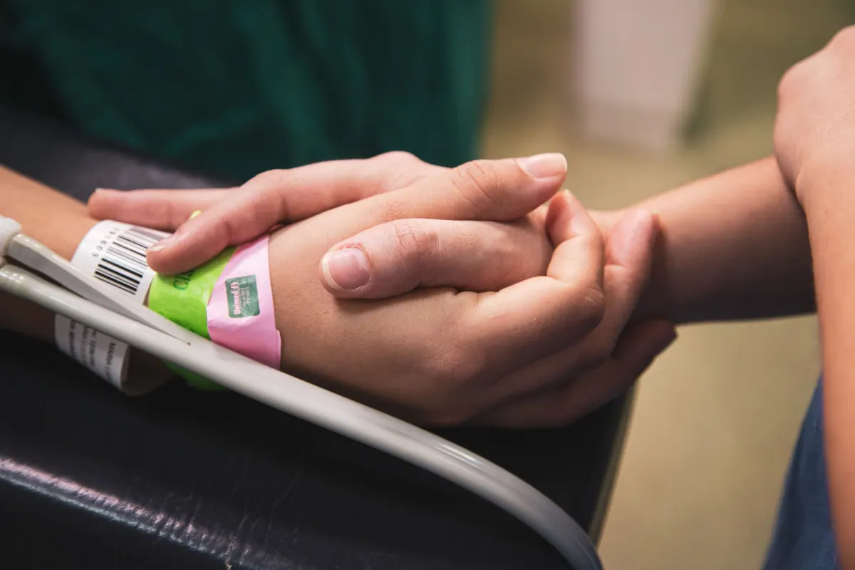 Close-up of hands offering comfort and support to a hospital patient
